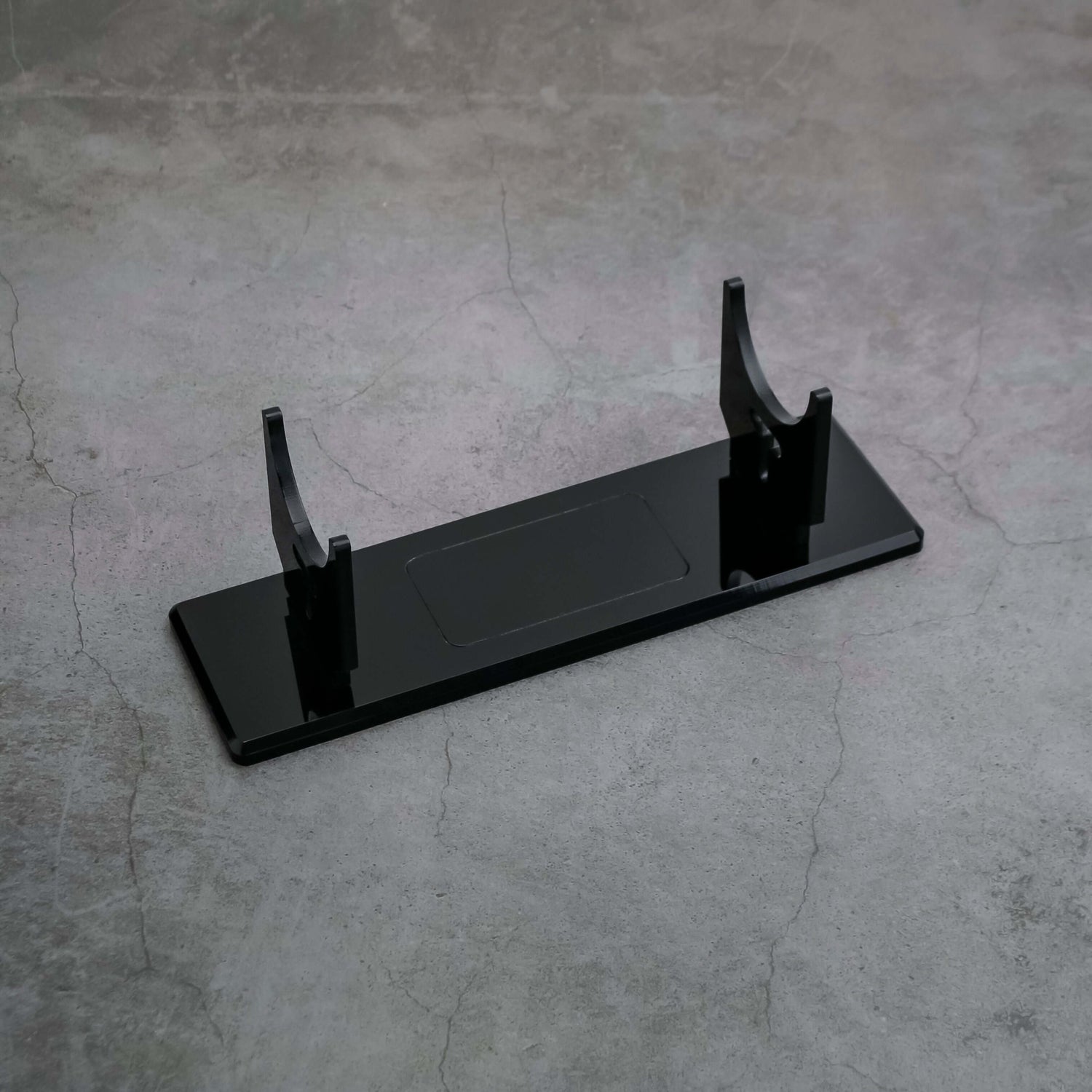 Black acrylic display stand designed for showcasing collectibles like sabers with stability and style.