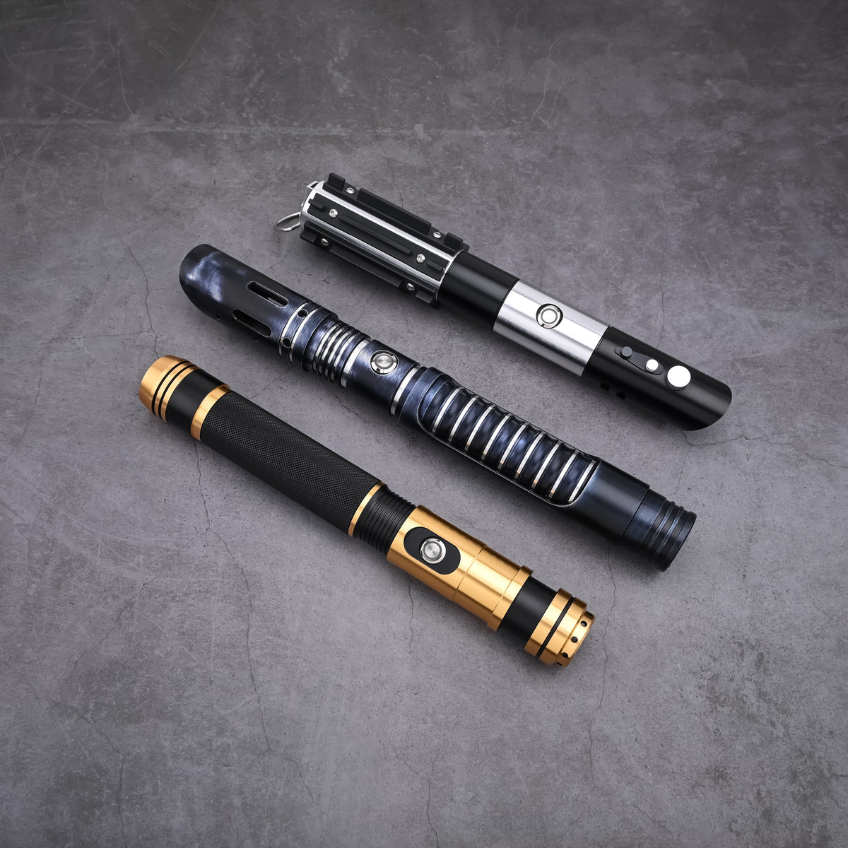 The Jedi Trinity lightsaber hilt bundle arranged on a textured surface