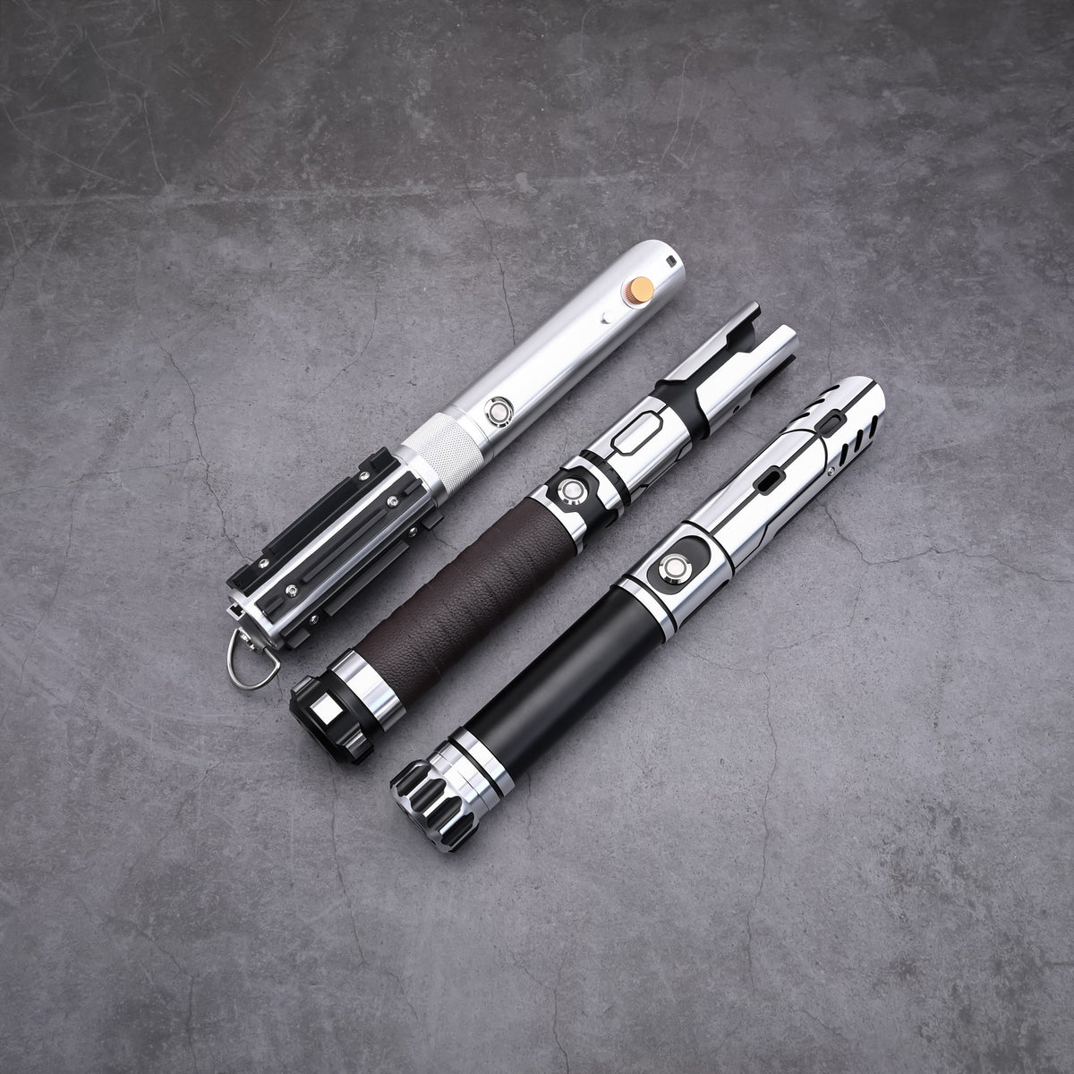 Detailed close-up of the Obsidian Elite Trinity lightsaber hilts arranged on a flat surface