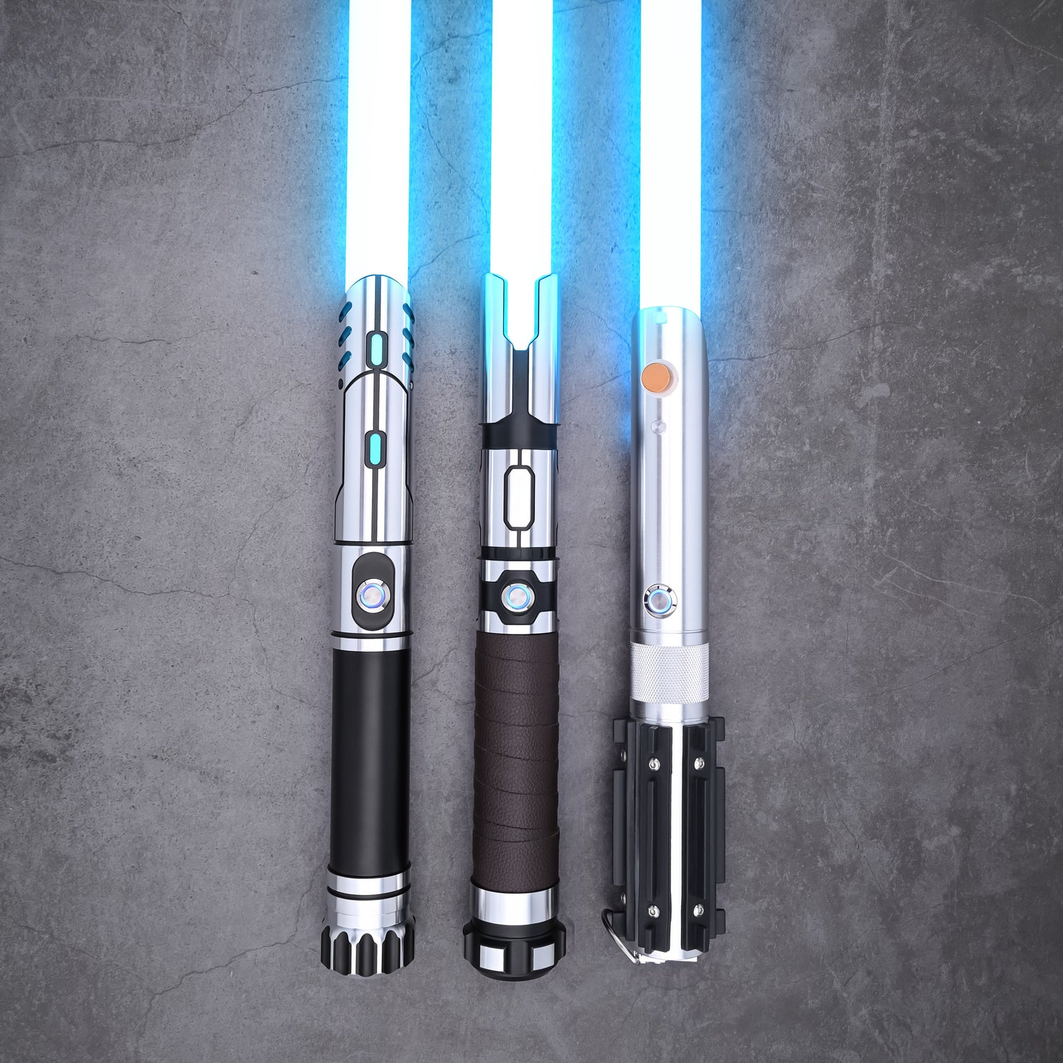 Three Obsidian Elite Trinity lightsaber hilts standing upright with blue blade illumination